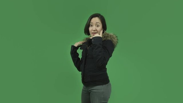caucasian girl with winter jacket isolated on green screen with call me hand sign