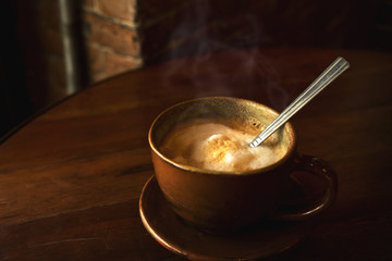 cup of hot coffee on table in cafe with morning light - vintage and dark color tone styles