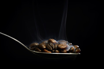 Scooping hot coffee beans with spoon.