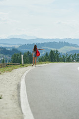 Pretty girl hitchhiking along the road
