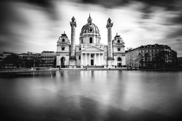 Fototapeta na wymiar View on st. Charles's church on Karlsplatz in Vienna. White and black image with long exposure technic with blurred clouds and glossy water.