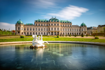 Fototapeta na wymiar View on Upper Belvedere palace with fontain in Belvedere historic building complex in Vienna. Long exposure technic with blurred clouds and glossy water