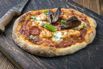 Meeresfrüchte Pizza auf altem Schneidebrett