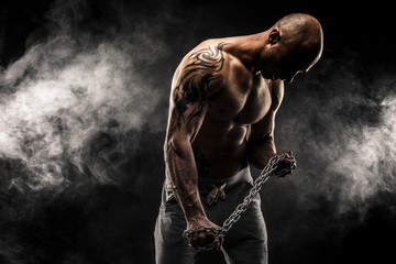 Strong bald man trying to tear metal chain
