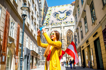 Jeune femme touriste avec drapeau autrichien faisant une photo de selfie avec la cathédrale Saint-Étienne dans le centre de Vienne