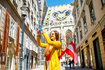 Crédence de cuisine en verre imprimé Vienne Jeune femme touriste avec drapeau autrichien faisant une photo de selfie avec la cathédrale Saint-Étienne dans le centre de Vienne