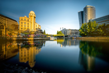 Fototapeta na wymiar Vienna cityscape with modern Uniqa and Urania tower on the water channel in the morning. Long exposure image technic with glossy water and reflection