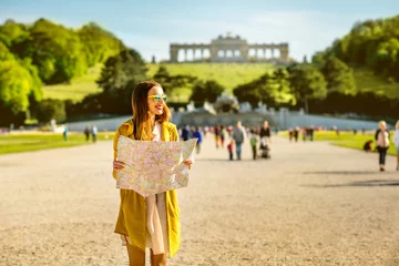 Deurstickers Wenen Young female tourist traveling with paper map in Schoenbrunn palace with Gloriette building on the background