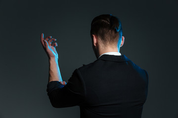 Back view of young man magician standing with raised hand