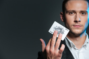 Portrait of handsome young magician holding ace card