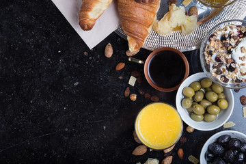 Obraz na płótnie Canvas Breakfast assorted yoghurt, granola, coffee, juice, croissant, olives. Appetizer mix with morning dishes. Healthy, fresh, delicious food on dark background. Top view. Copy space.