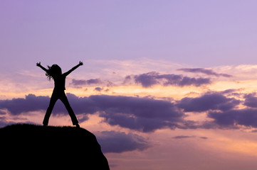 Silhouette of the happy woman on a hilltop in the evening