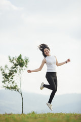 Happy jumping Asian girl on meadow.