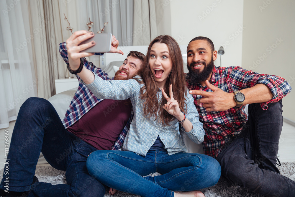 Sticker Happy young friends sitting and taking selfie at home