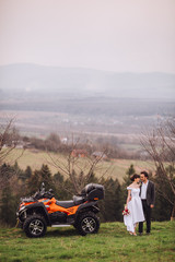 Obraz premium Happy beautiful couple near four-wheeler ATV in foggy nature. Smiling looking into distance