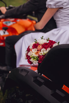 Couple sitting on four-wheeler ATV. View from the back with flowers.
