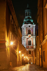 Fototapeta na wymiar A church and cobbled street at night in Poznan ..
