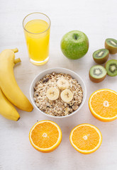 Granola, bananas, glass of orange juice and kiwi