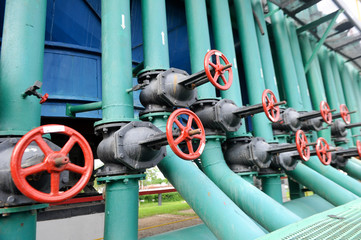 Red faucet with steel pipe in natural gas compressor station in summer day