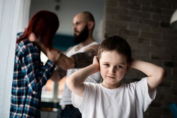Sad, desperate little boy during parents quarrel