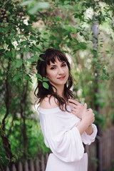 Portrait of a beautiful brunette woman outdoors in a white dress. Close-up portrait. Summer outdoor portrait