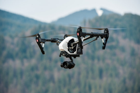 drone with high resolution digital camera/White drone with digital camera flying in sky over mountain