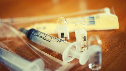 Syringe and empty vials on table macro selective focus shallow dof toned image
