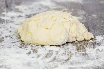 Macro view of bread dough and white flour on rustic wooden cutting board, shallow DOF