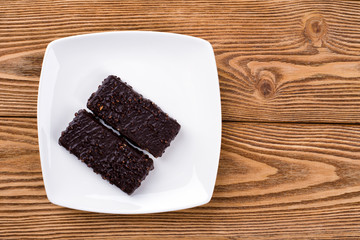 Two waffles in chocolate on a square plate on a wooden background 