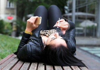 young woman smoking while relaxing on a bench