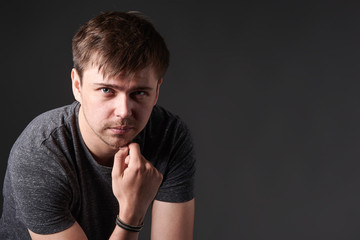 Portrait of casual young man with light beard, on dark background