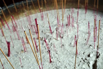 Incense sticks planted in sand at the entrance of a Buddhist temple