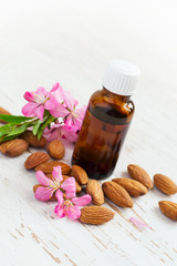 Almond oil in a small bottle and scattered almonds nuts and flow