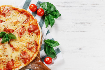 Half of Hot true PEPPERONI ITALIAN PIZZA with salami and cheese. TOP VIEW Tasty traditional pepperoni pizza on board on white wooden table. Copy space for your logo. Ideal for commercial 