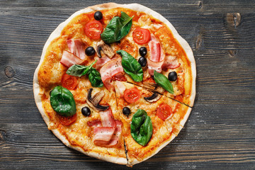Top view of Italian rustic PIZZA mushrooms, basil, tomato, olives and cheese. Cut off a piece and pushed. Dark wooden table background. Look as Prosciutto, Capricciosa, Funghi, Cotto PIZZA.