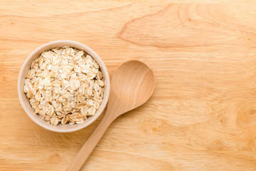 Rolled oats in a cup and wooden spoon on a wooden background