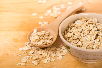 Obraz na płótnie Canvas Rolled oats in a wooden spoon and cup on a wooden background