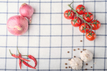 frame of pepper, garlic, onion, tomatoes on squared cloth table