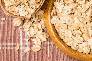 Rolled oats in a wooden spoon and cup on cotton background