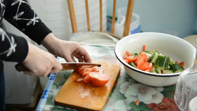 Woman hands slicing tomato in a rustic kitchen