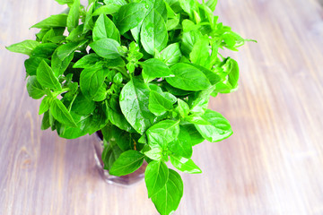 Wet fresh basil (herbs) in the cone of paper on a wooden table