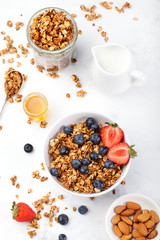Healthy breakfast Fresh granola, muesli in bowl with milk and berries on a white background
