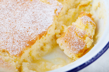 Lemon pudding cake with fresh lemons on a white wooden background.