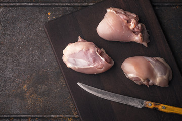 Pieces of chicken meat and a knife on a wooden board