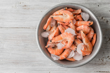Shrimp and ice in the aluminum bowl on white boards