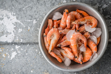 Shrimp and ice in the aluminum bowl on a metal background