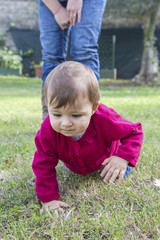 Naklejka na ściany i meble Little girl crawling on grass
