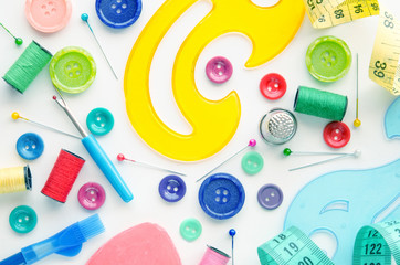 Sewing kit on the white background. Colorful set consisting of measuring tape, ruler, pins, buttons, bobbins, pencils. 