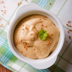 Top view on white bowl full of orange mustard