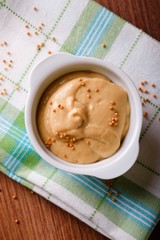 Top view on white bowl with orange mustard on green towel